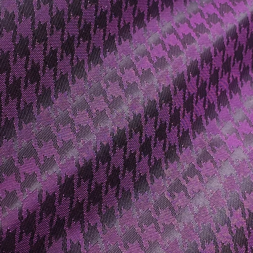 Purple and black houndstooth fabric pattern, showcasing a classic textile design with a bold color contrast.