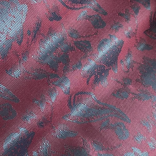Close-up of a burgundy fabric with an intricate blue floral pattern, showcasing detailed texture and design.