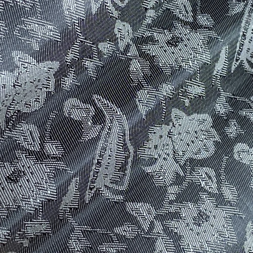 Intricate black and white floral pattern on textured fabric background, showcasing detailed woven design.