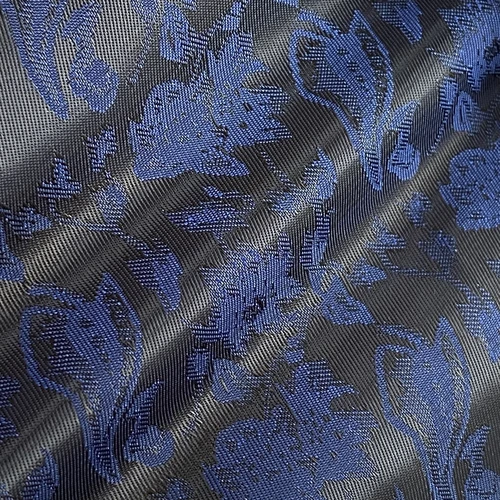 Blue floral jacquard fabric with intricate patterns on a black background, highlighting texture and design.
