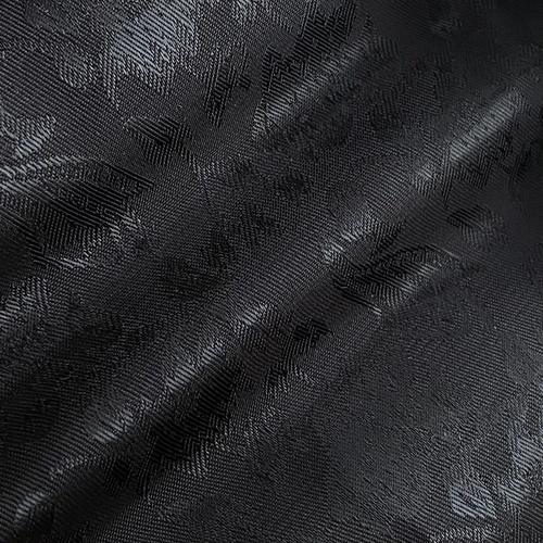 Close-up of textured black fabric with floral patterns, showcasing intricate design details and elegant craftsmanship.