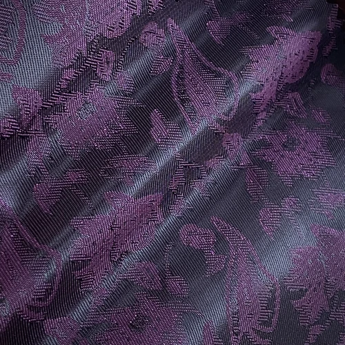 Close-up of a textured fabric with an intricate purple floral pattern.
