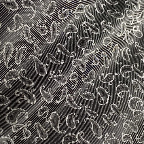 Close-up of shiny, metallic patterned fabric with swirling abstract designs. Ideal for fashion or textile projects.