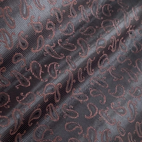 Close-up of black fabric with intricate paisley pattern and subtle sheen. Ideal for luxury fashion or interior design.