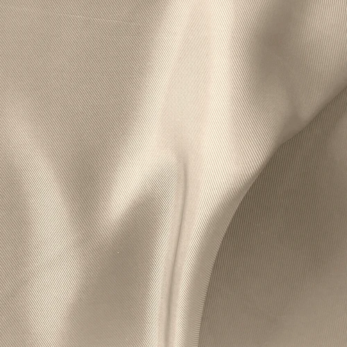 Close-up of smooth beige fabric texture with soft folds, showcasing its intricate weave and luxurious appearance.