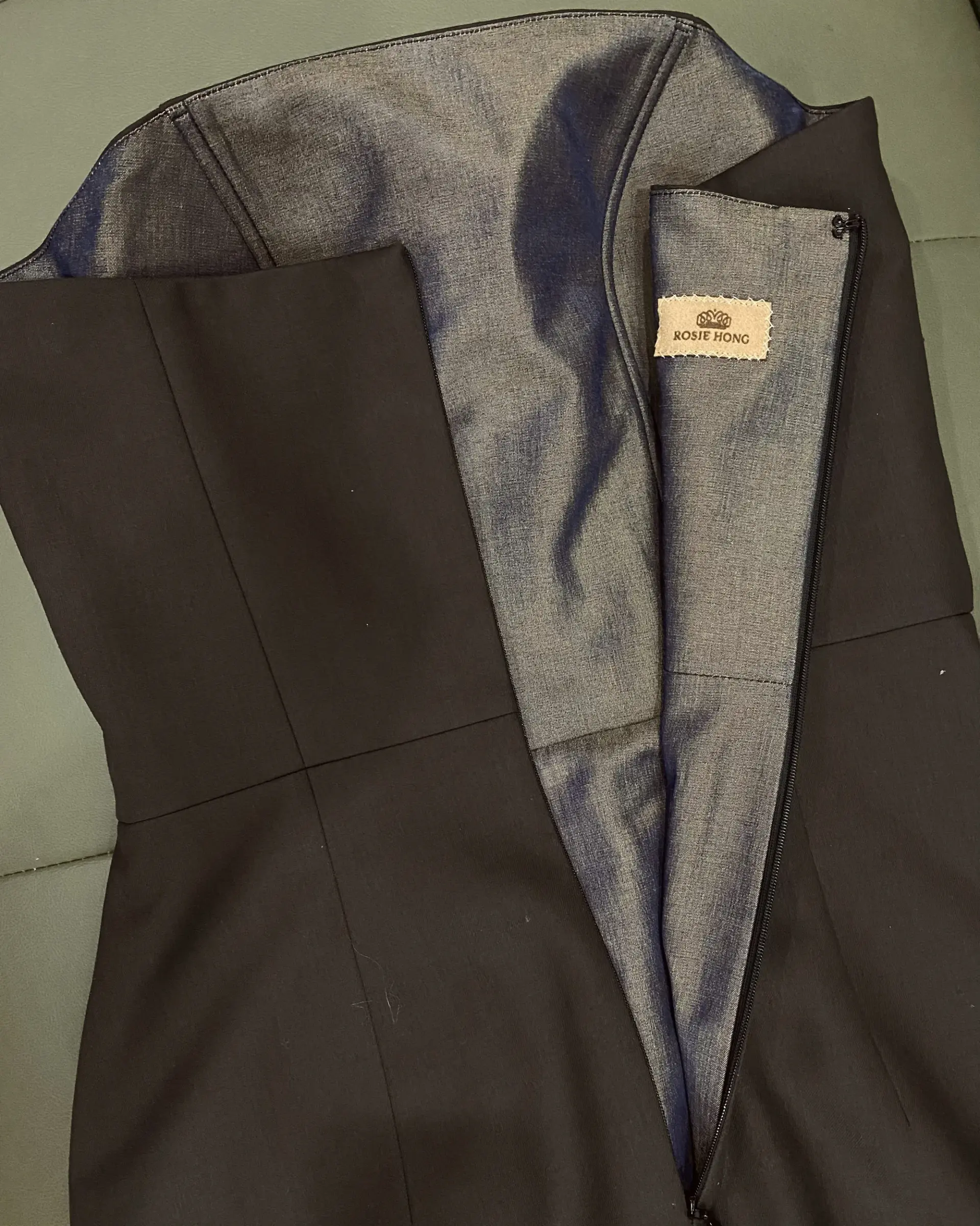 Black sleeveless dress with open back on display, highlighting the “Rosie Hong” label on inner lining.