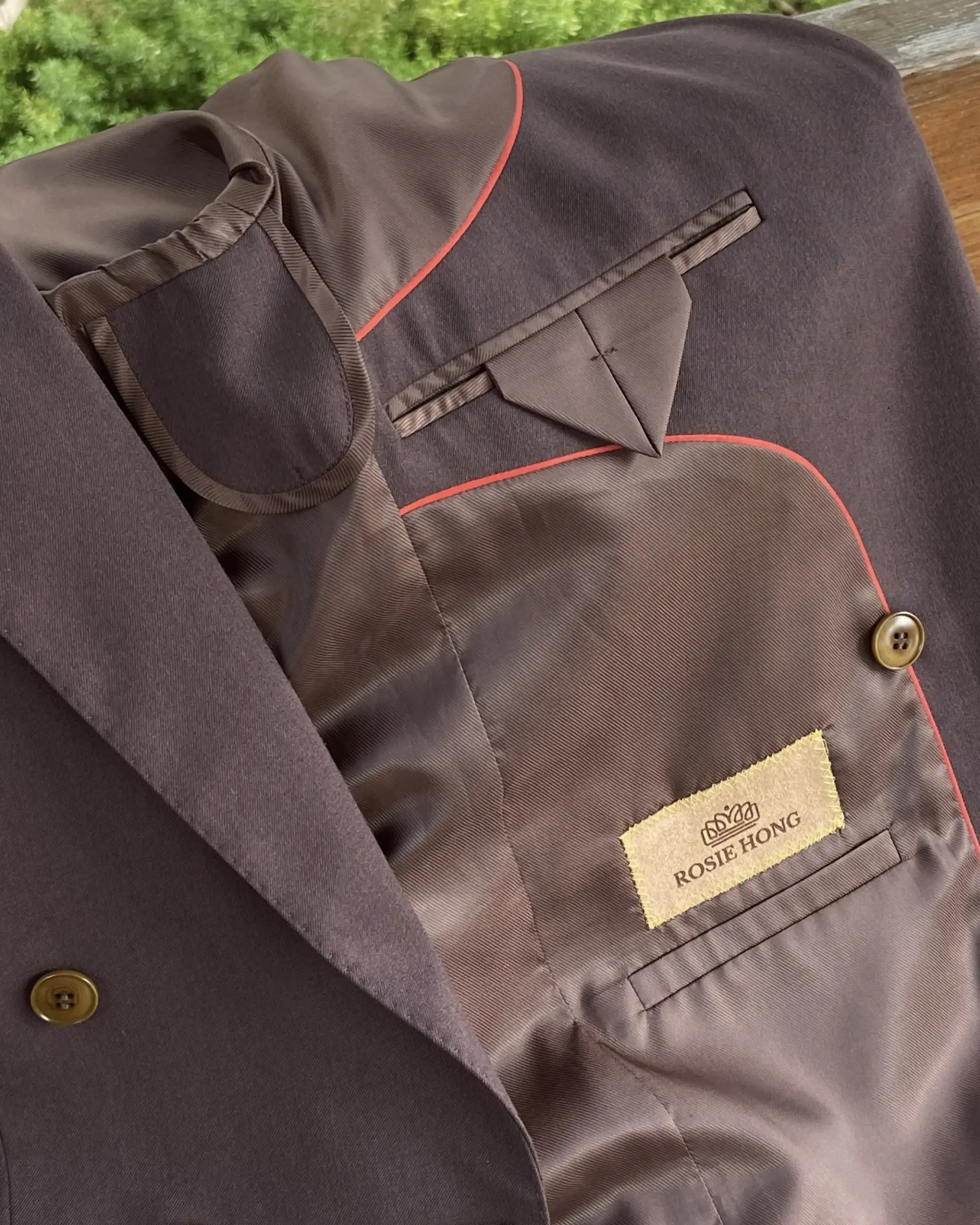 Brown blazer with red trim and Rosie Hong label, featuring detailed interior pocket design.
