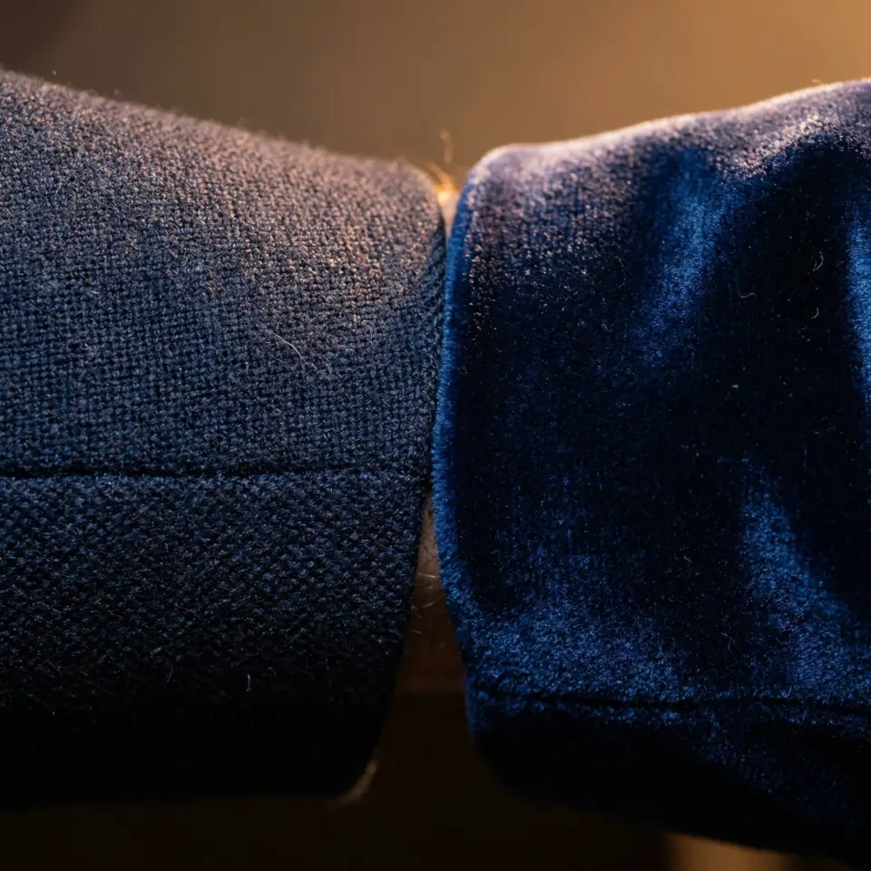 Close-up of a dark blue velvet and textured fabric sleeve, showcasing luxurious textile contrast.