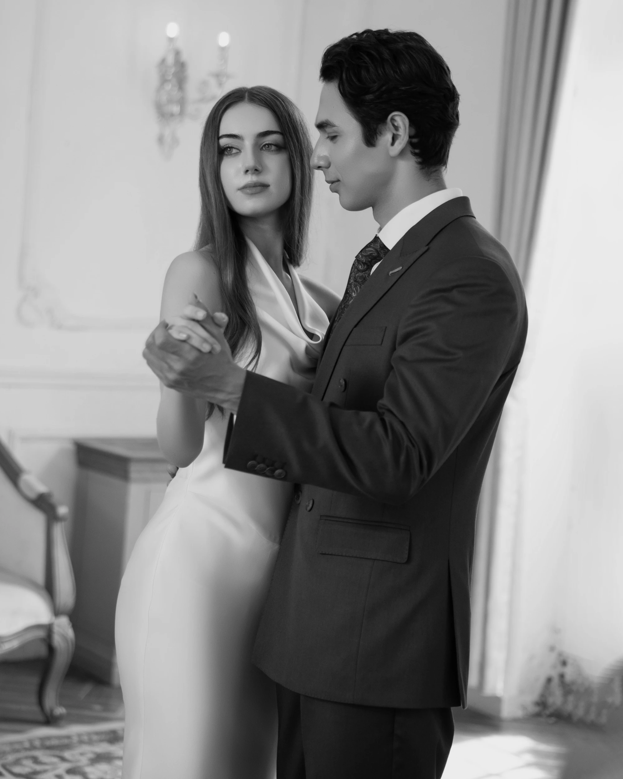 Elegant couple sharing a dance in formal attire, capturing a timeless moment in black and white.