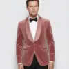 Man in stylish pink velvet tuxedo with black bow tie, showcasing upscale fashion.