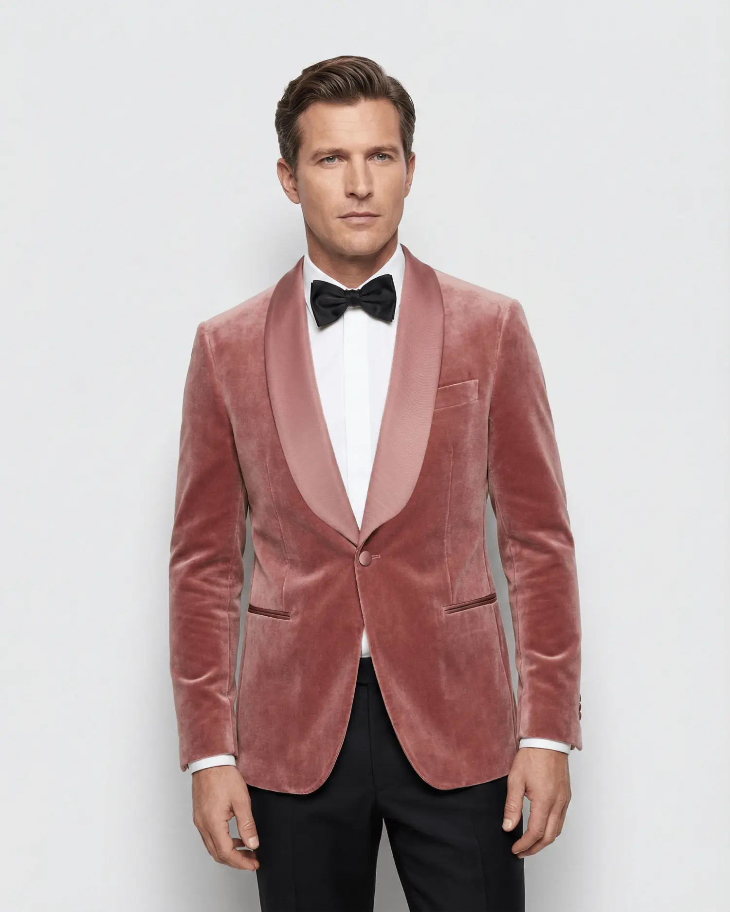 Man in stylish pink velvet tuxedo with black bow tie, showcasing upscale fashion.