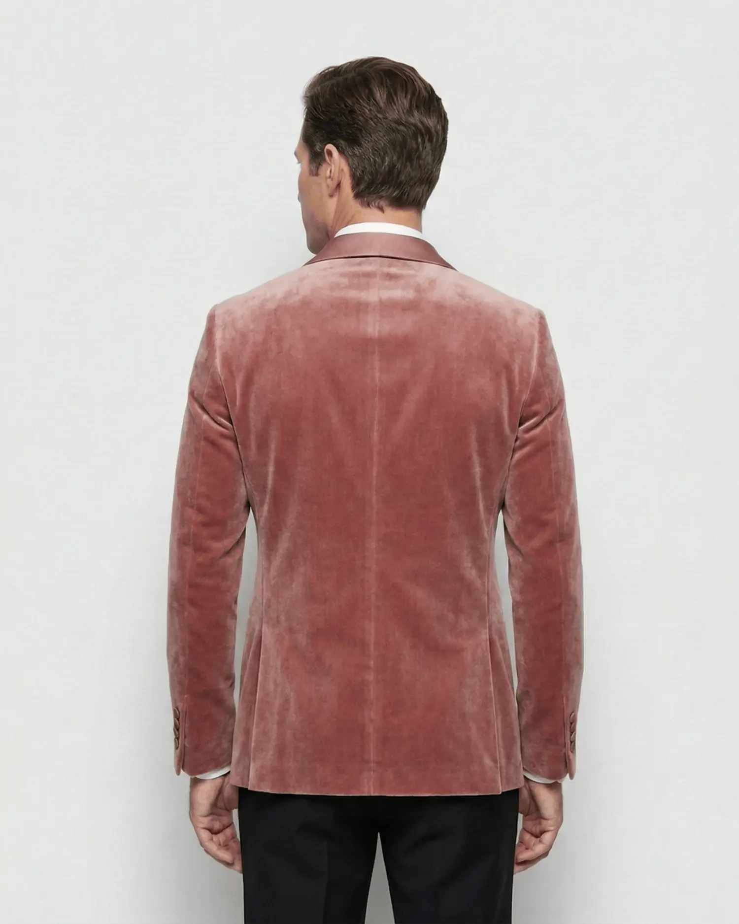 Man wearing a pink velvet blazer, viewed from the back, standing against a neutral background.