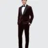 Man in a burgundy velvet tuxedo with black lapels, white shirt, and bow tie, standing against a light gray background.