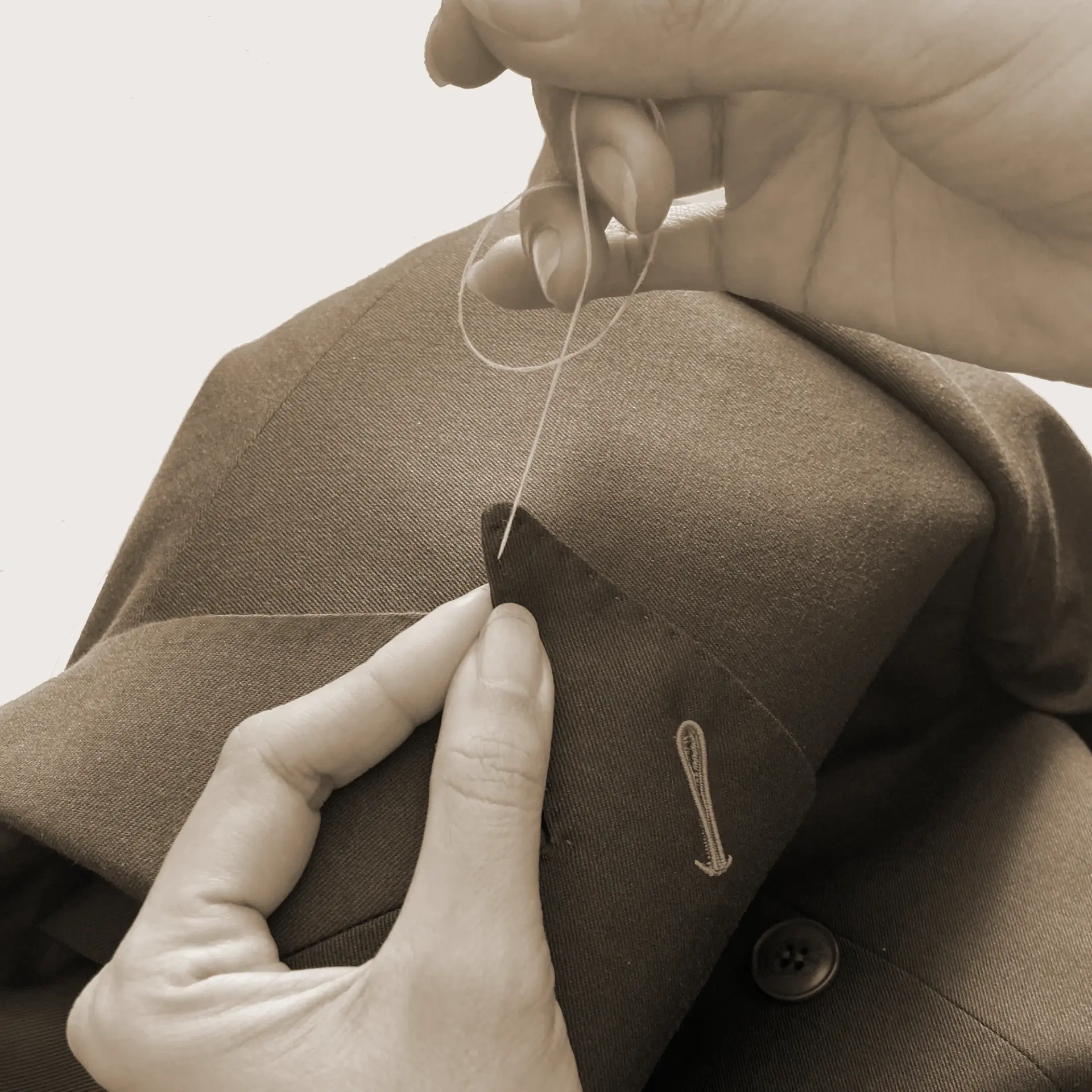 Hand sewing a brown jacket with needle and thread for tailoring.