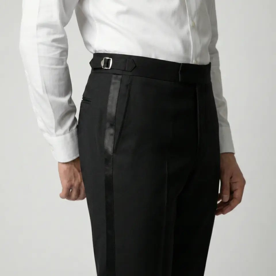 Man in white shirt wearing tailored black tuxedo pants with side adjusters.