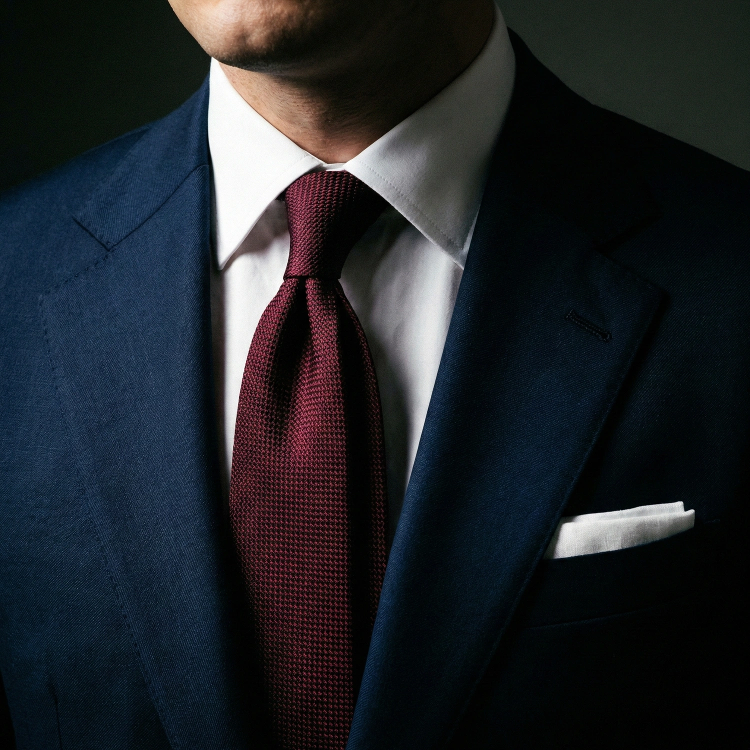 Man in a navy suit with a white shirt and burgundy tie, exuding elegance and professionalism.
