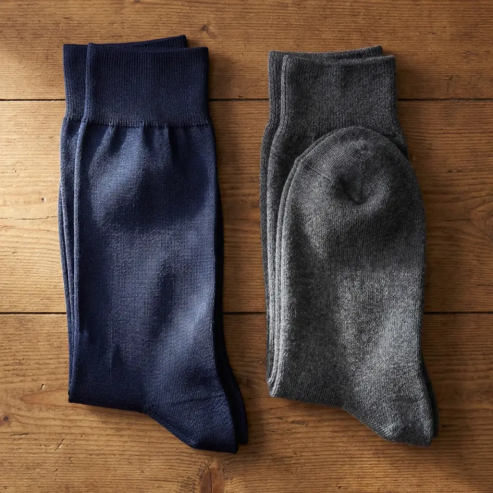 Two pairs of folded socks, navy blue and gray, on a wooden surface.