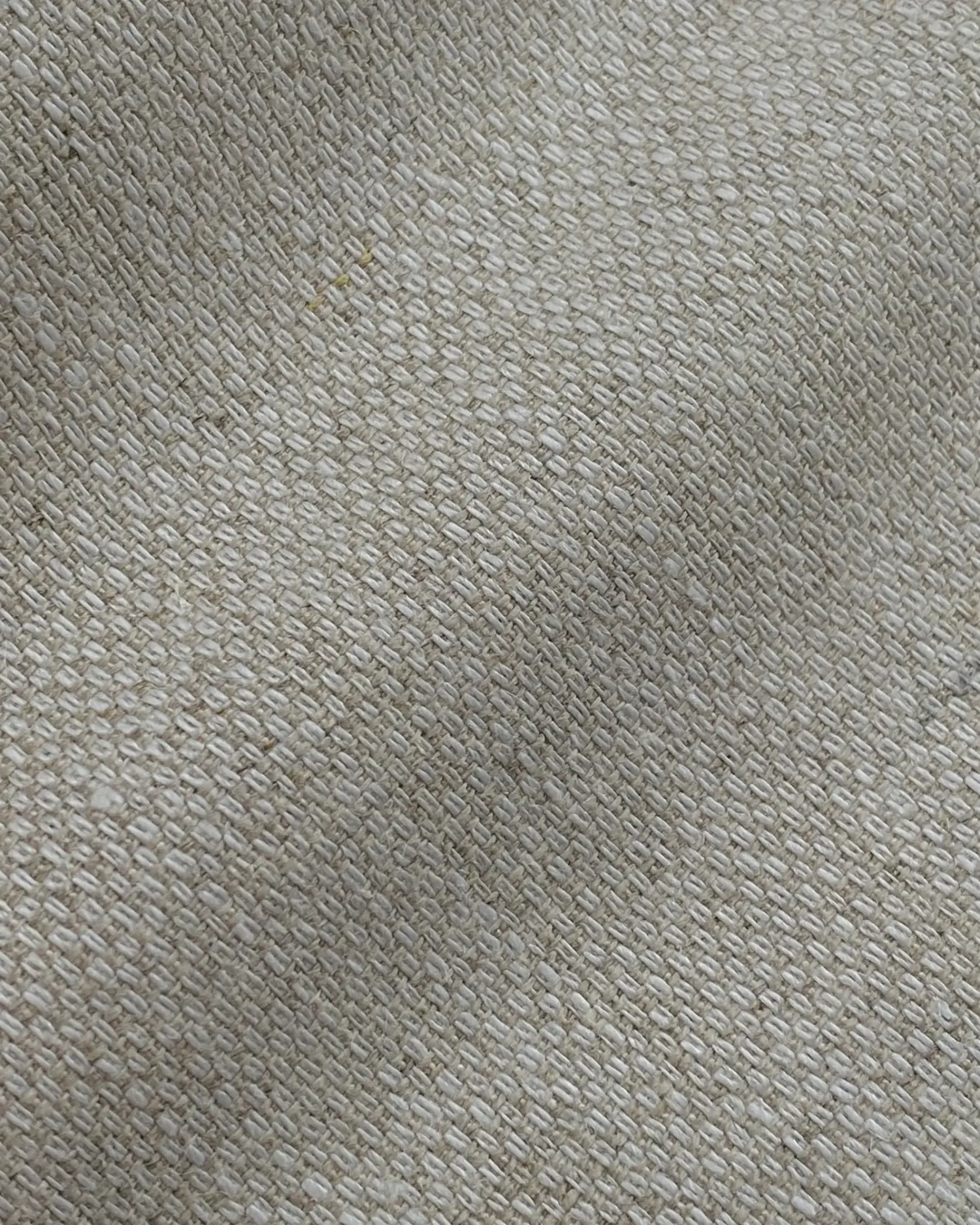 Close-up texture of woven fabric in beige tones, showing intricate pattern and detail.