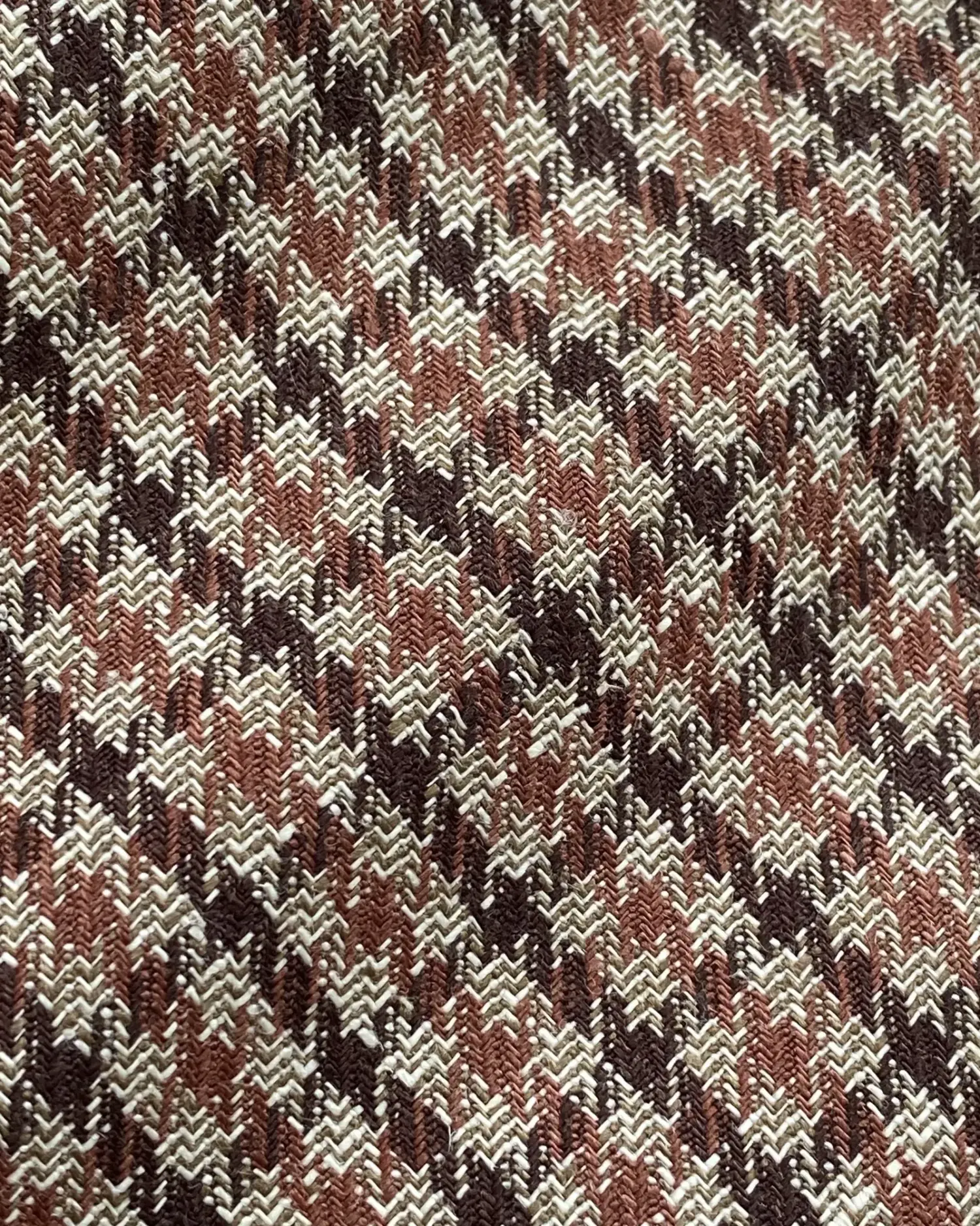 Close-up of a red and brown houndstooth fabric pattern, showcasing its intricate design and texture.