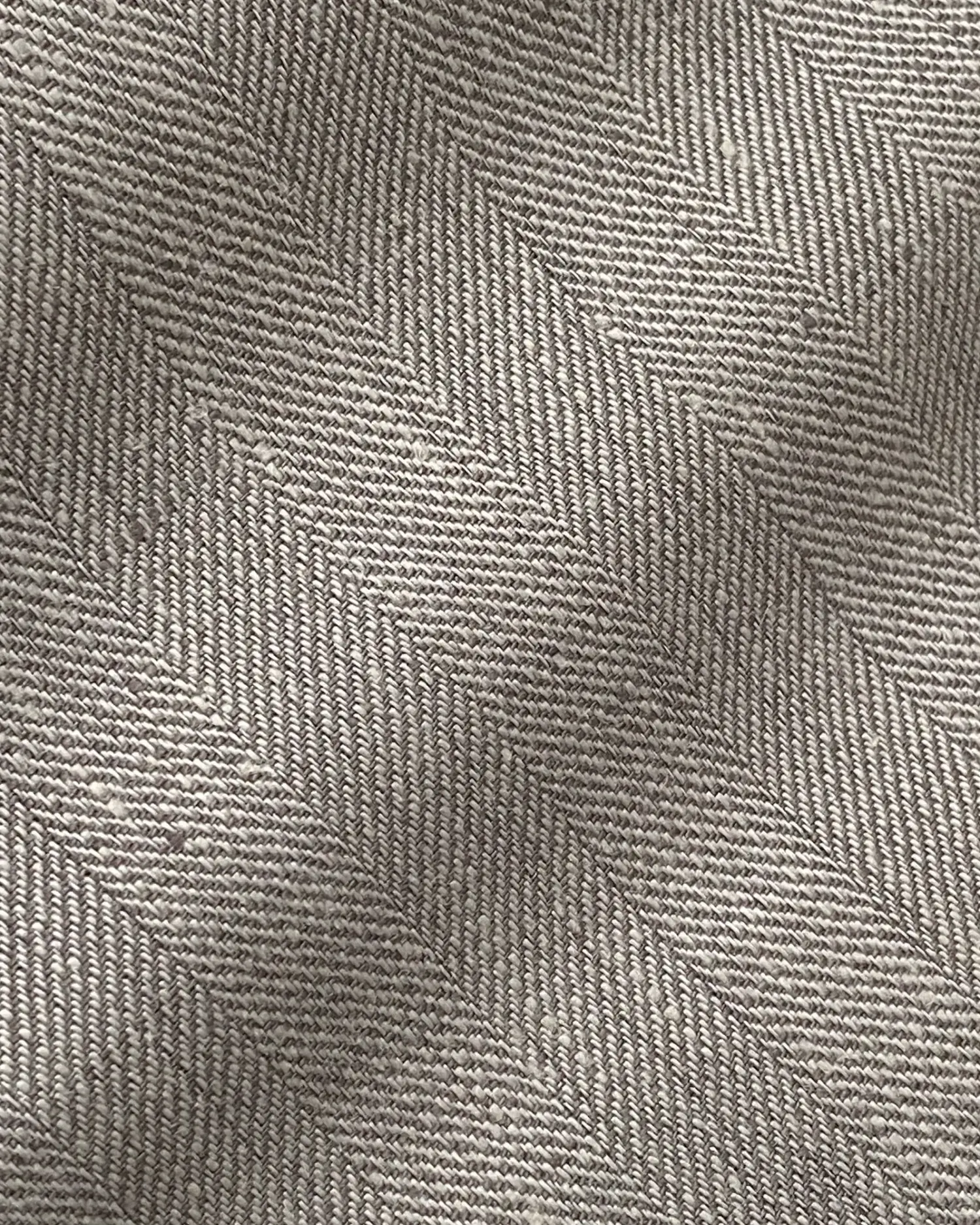 Close-up of gray herringbone fabric texture, showing intricate woven pattern and fine detailing.