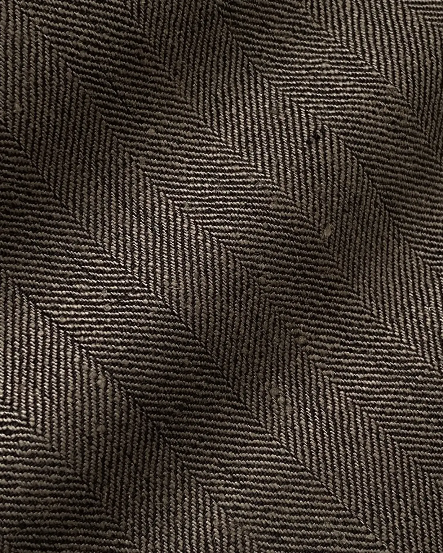 Close-up of a herringbone wool pattern in brown tones, showcasing detailed textile texture and diagonal design.