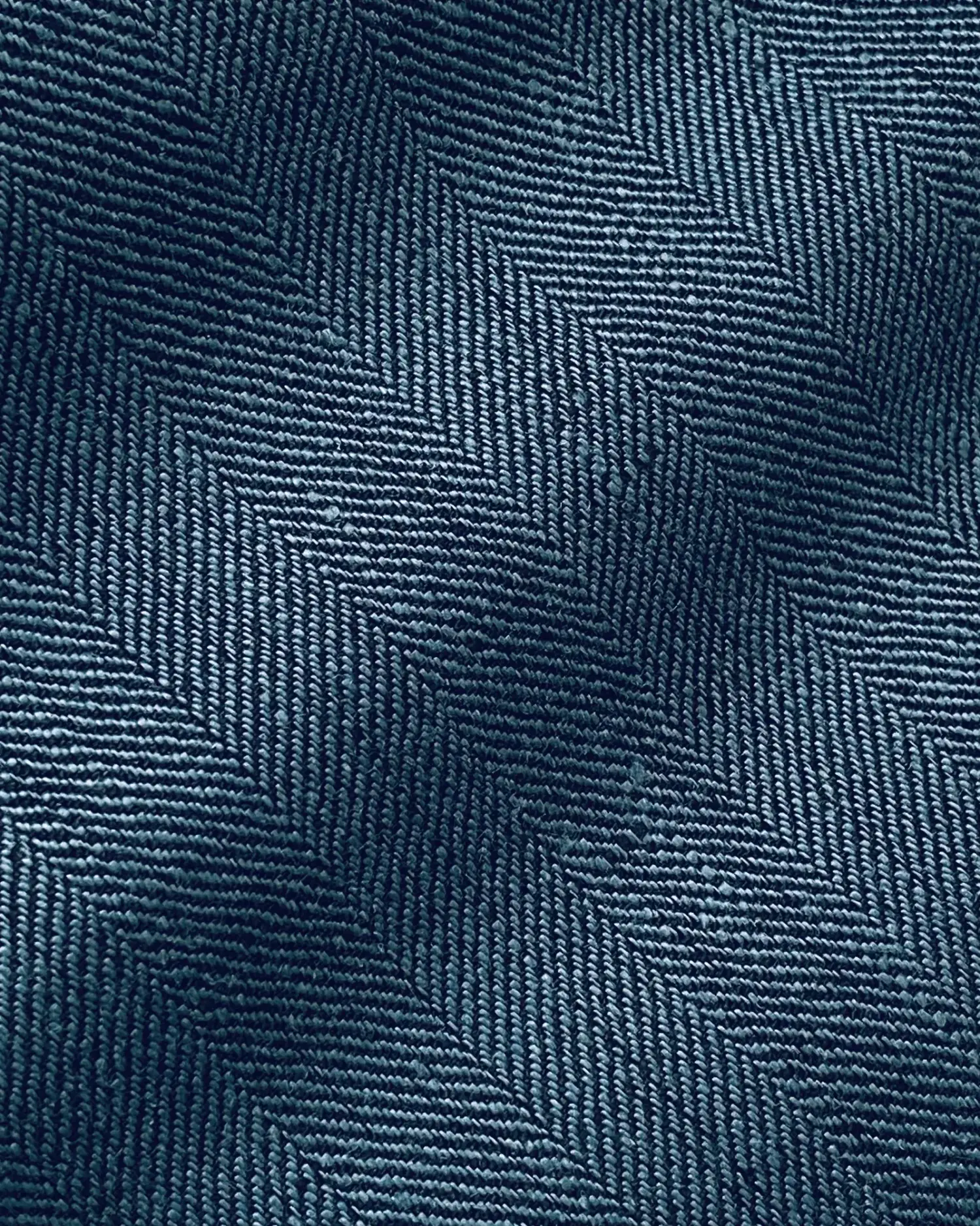 Close-up of blue herringbone fabric texture, showcasing intricate zigzag weave pattern for fashion and design inspiration.