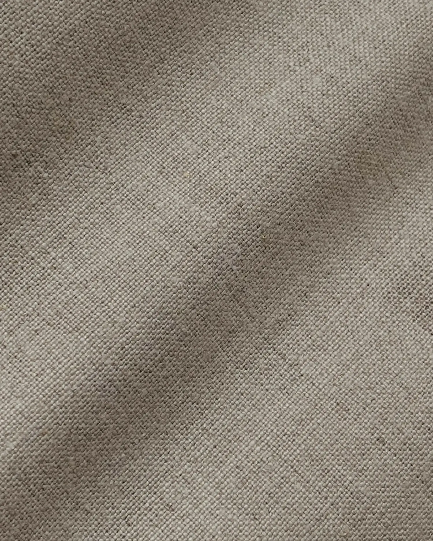 Close-up of beige linen fabric texture with visible weave, showing natural fibers and subtle variations in color.