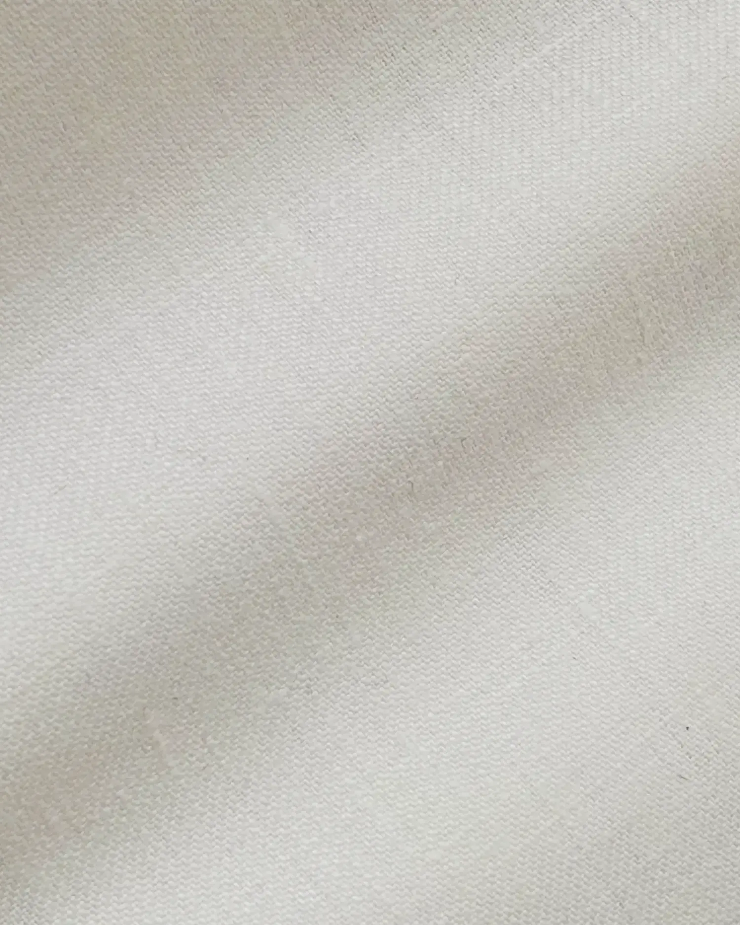 Close-up of smooth, light beige plain-textured fabric with soft lighting.