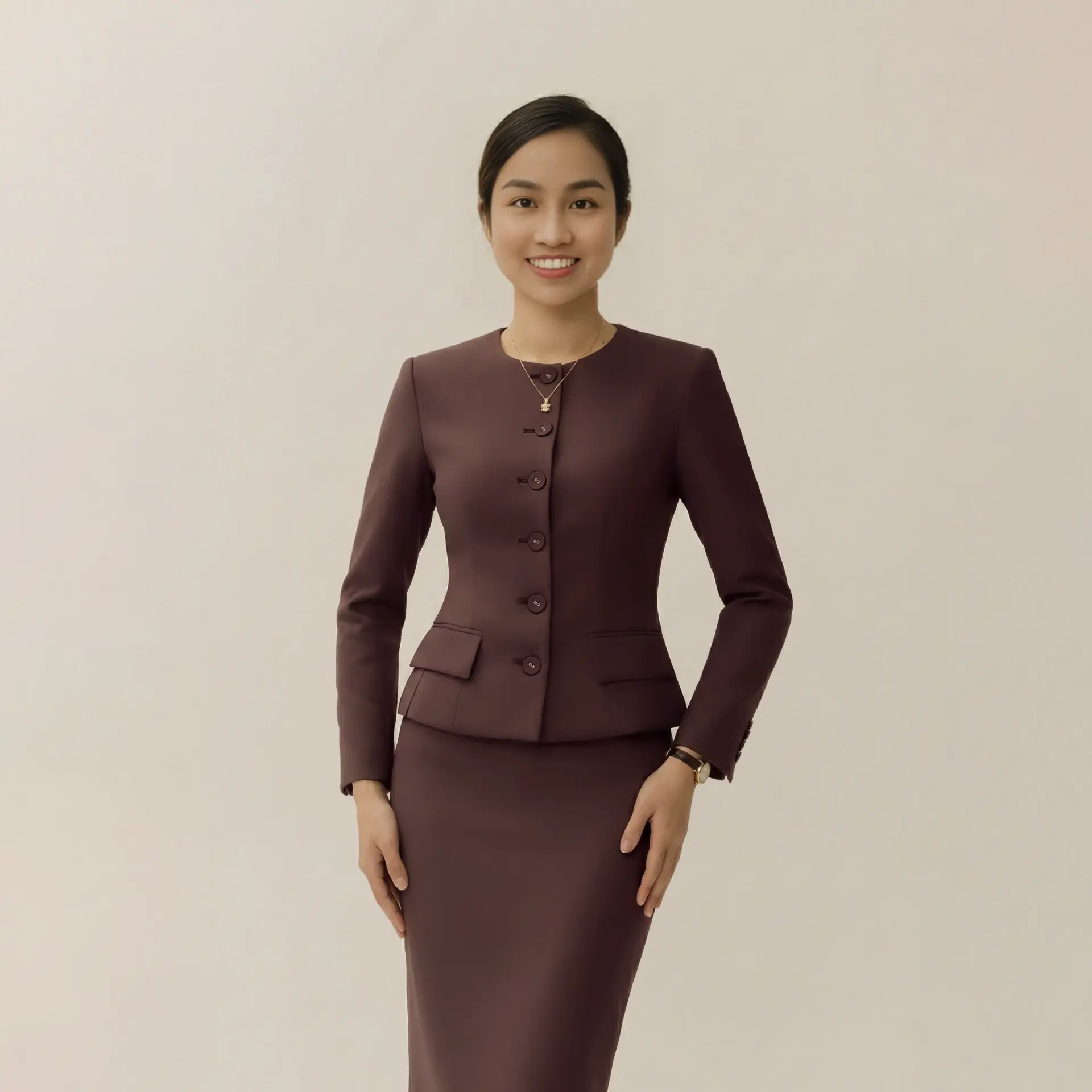 Rosie Hong founder_Professional woman in a tailored maroon blazer and skirt, smiling confidently against a plain background.